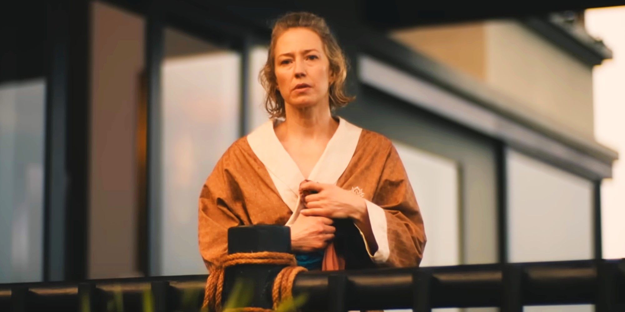 Carrie Coon as Laurie wearing a robe and looking over a balcony in The White Lotus season 3 episode 8