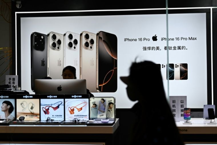 A woman passes in front of an electronics store in a shopping center in Beijing on April 13, 2025 (AFP / Pedro Pardo)