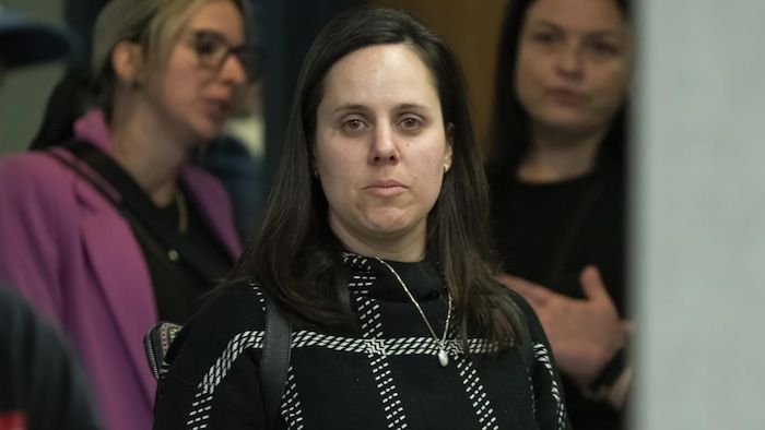 Marie-Christine Cloutier stares at the objective in a corridor of the Laval courthouse, surrounded by other women.