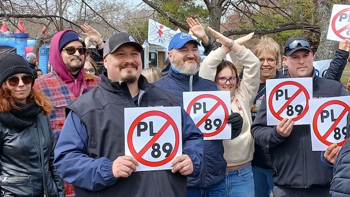 A group of people protests with its arms and signs prohibiting PL-89.