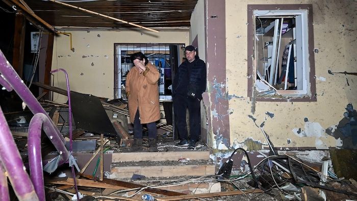 People in front of a partially destroyed house.