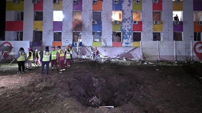 Ukrainian rescuers work on a crater near a residential building after a drone attack on Kharkiv early on May 3, 2025.