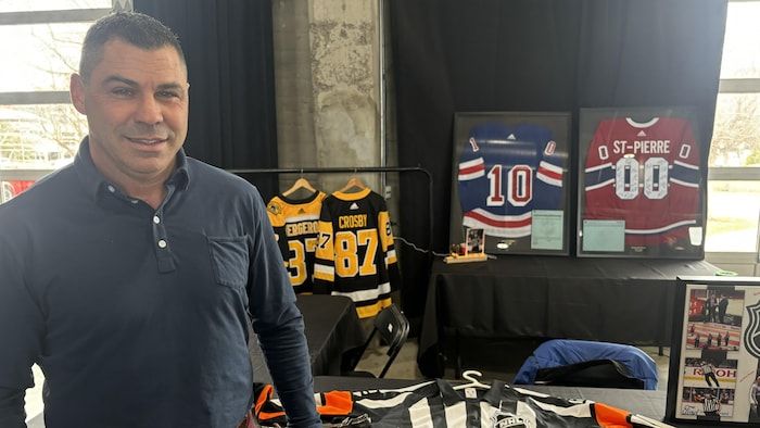 A man in front of a kiosk where hockey sweaters are.