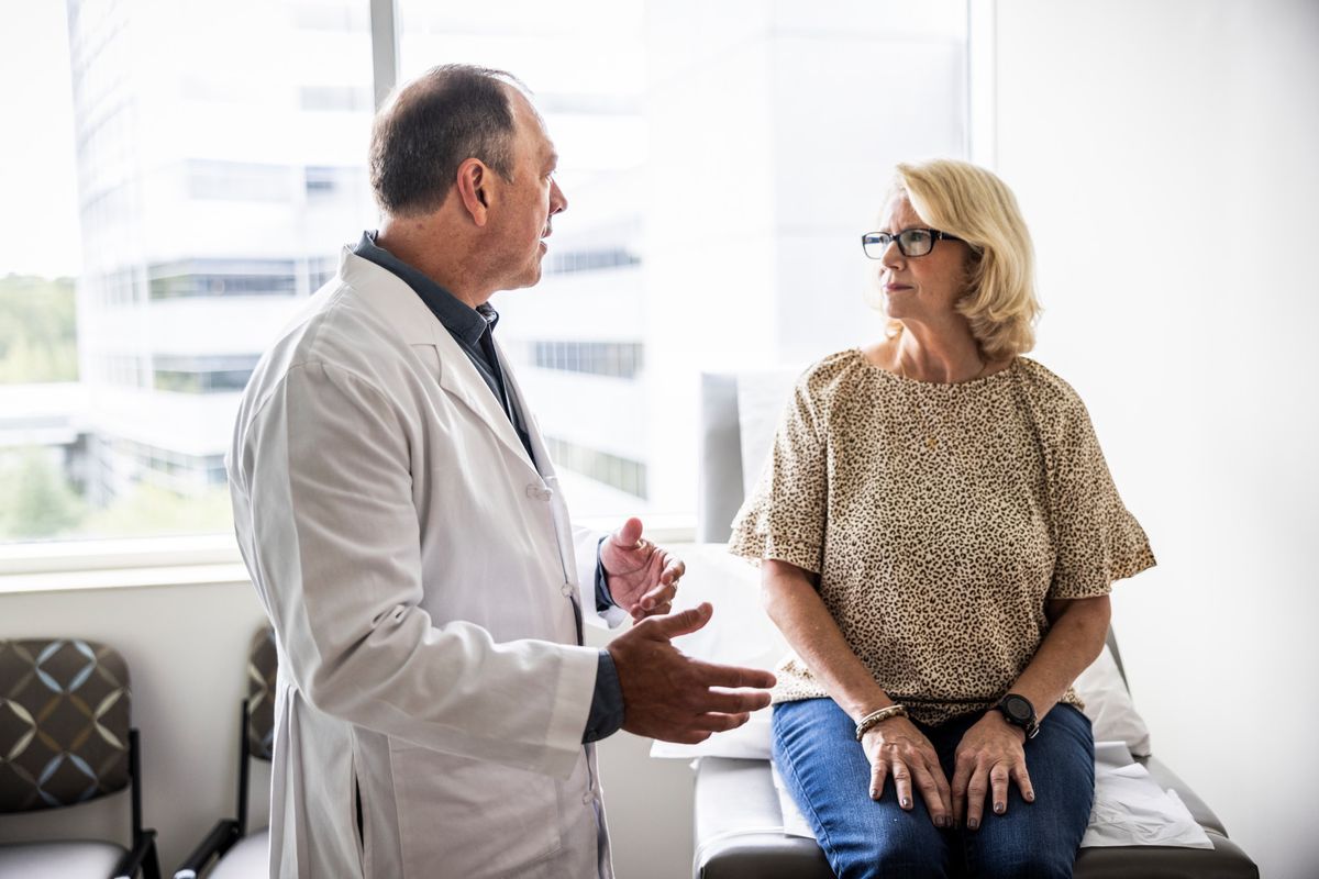 An elderly doctor consults a senior woman in a light examination room. An elderly doctor consults a senior woman in a light examination room.