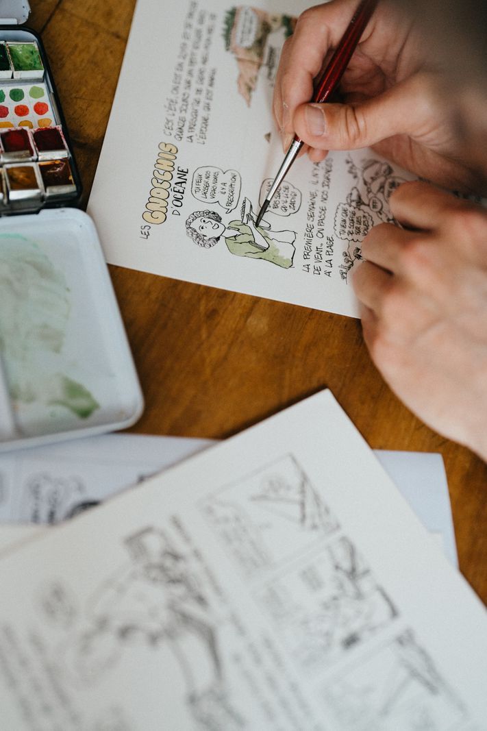 No one drawing sketches on paper with a brush, surrounded by color palettes. No one drawing sketches on paper with a brush, surrounded by color palettes.