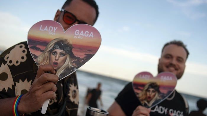 Two people hold fans bearing the image of Lady Gaga.