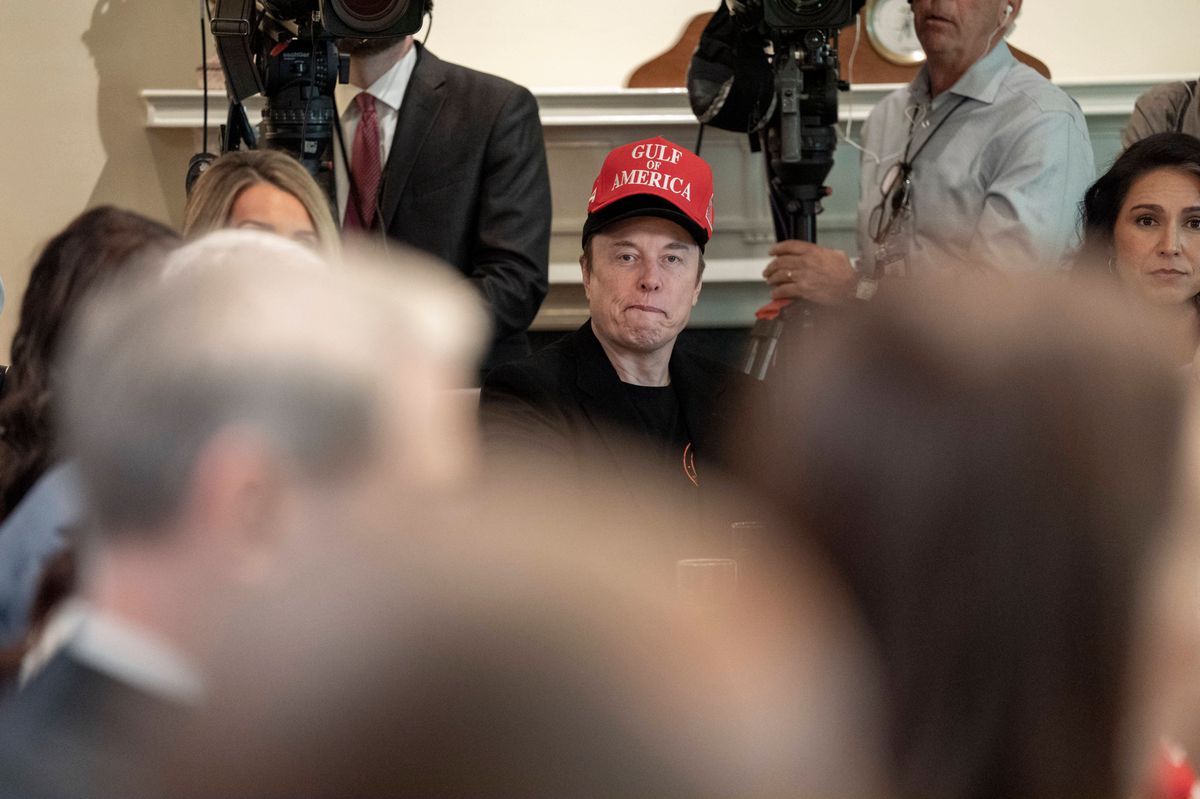 Elon Musk during a meeting from the cabinet to the White House, wearing a red cap with the inscription 'Gulf America', surrounded by participants and media. Elon Musk during a meeting from the cabinet to the White House, wearing a red cap with the inscription 'Gulf America', surrounded by participants and media.