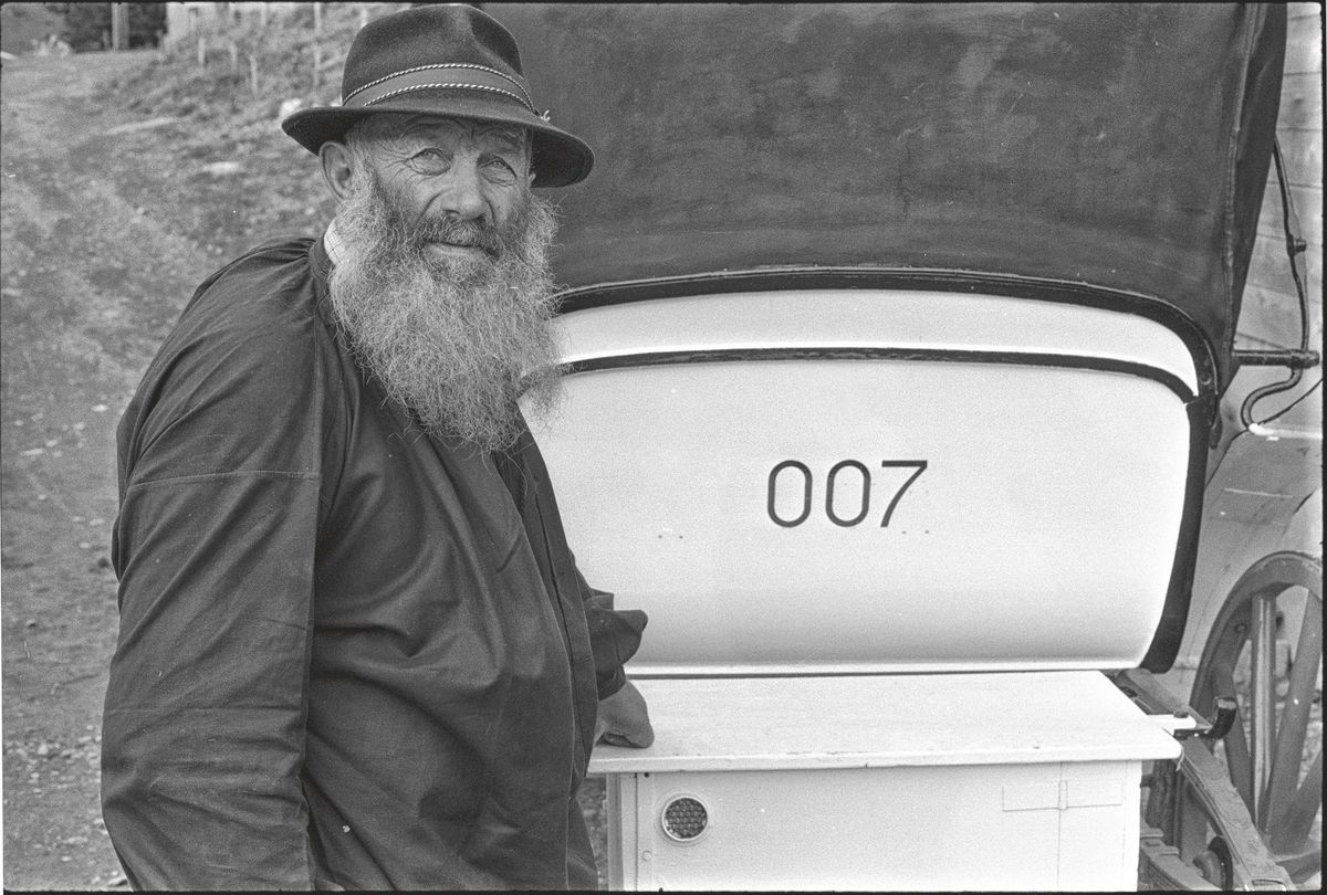Bearded man wearing a hat next to a carriage with the number 007 on the rear seat. Bearded man wearing a hat next to a carriage with the number 007 on the rear seat.
