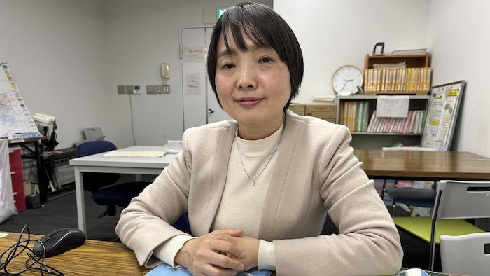 A woman sitting at an office looks at the camera.