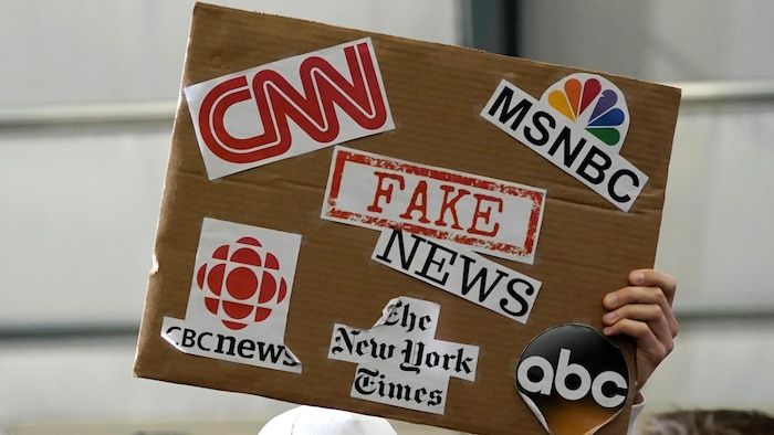 An supporter of President Donald Trump brandished a sign associating false news with media such as CNN, CBC News and the New York Times.