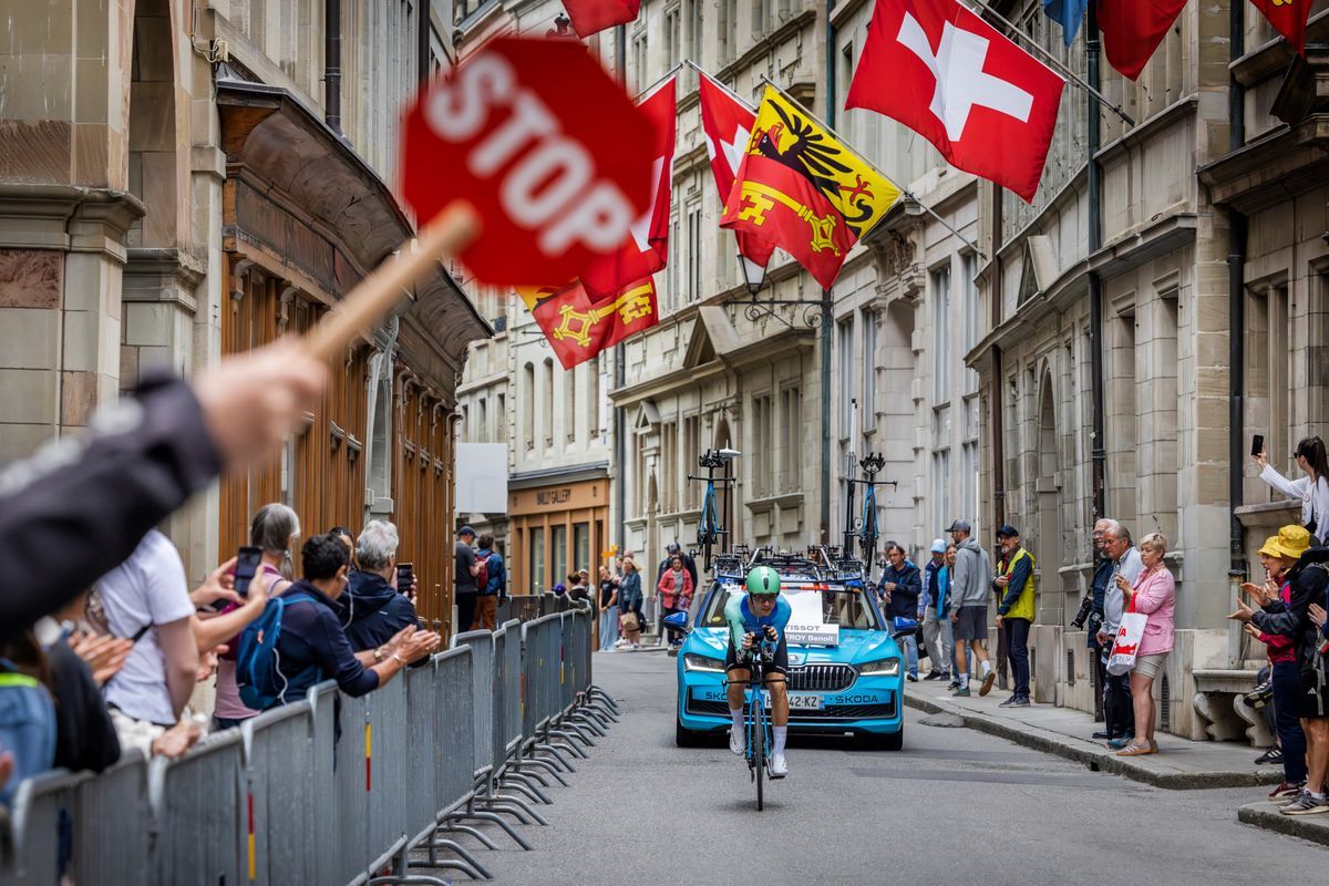 Cycling runner during the last stage of the Tour de Romandie 2025 in the old town of Geneva, with applauding spectators and floating Swiss flags. © Magali Girardin Cycling runner during the last stage of the Tour de Romandie 2025 in the old town of Geneva, with applauding spectators and floating Swiss flags. © Magali Girardin
