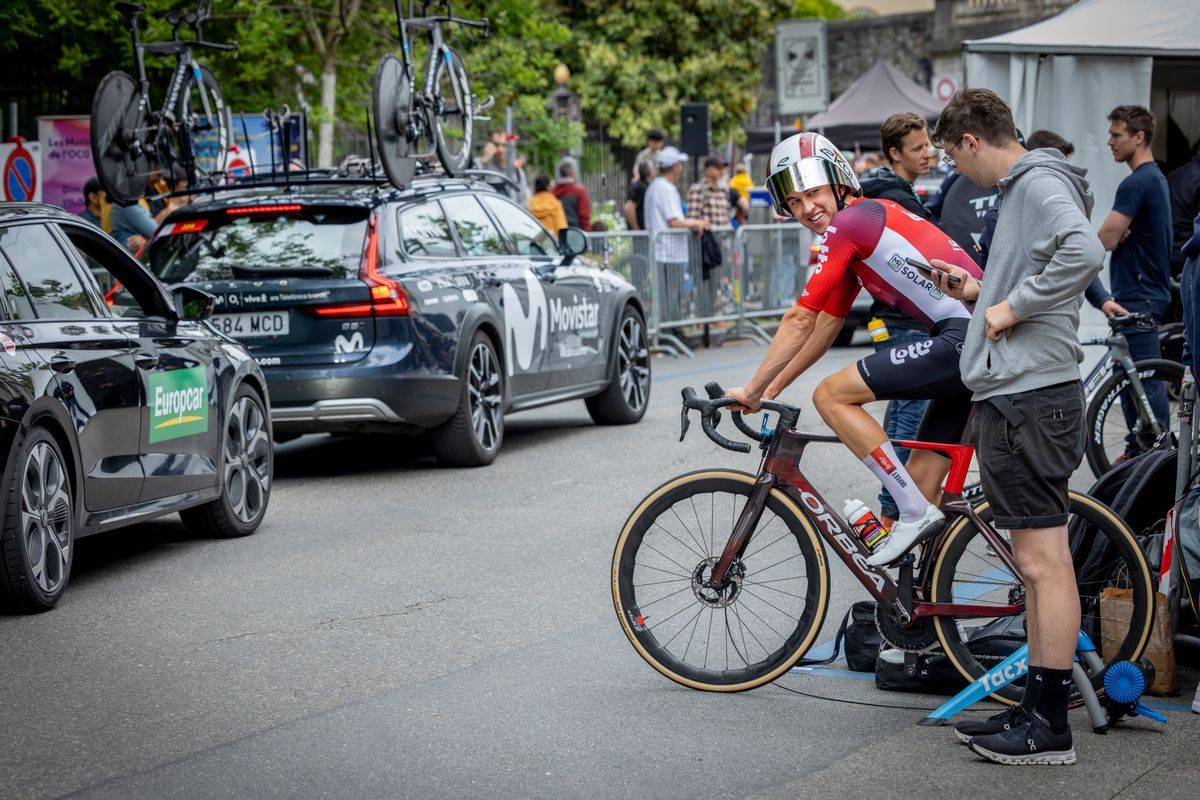 Cycling runner on Home Trainer during the last stage of the Romandie Tour in Geneva, in the middle of the old town, surrounded by support teams and vehicles. Cycling runner on Home Trainer during the last stage of the Romandie Tour in Geneva, in the middle of the old town, surrounded by support teams and vehicles.